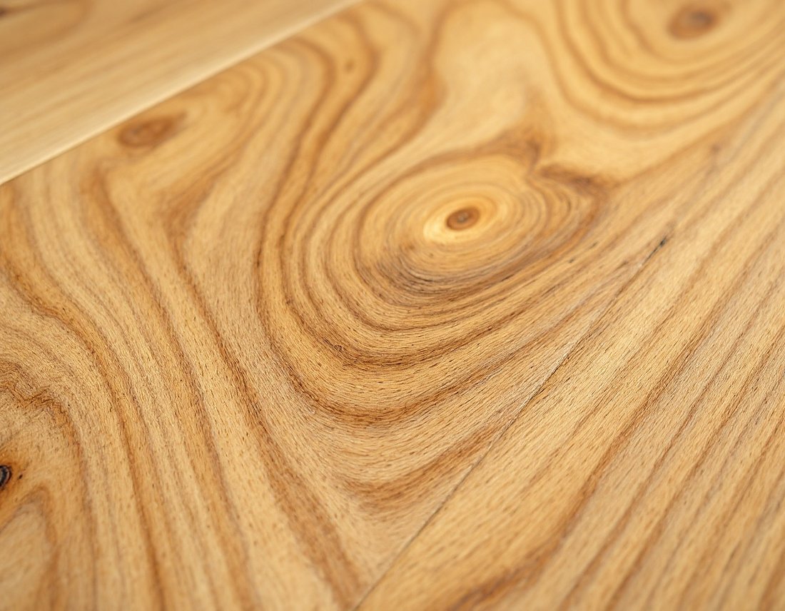 Close-up of genuine warm honey-oak solid hardwood flooring showing natural cathedral grain and a satin finish.